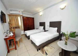 MandanouMiliet HOTEL的一间有两张床、一张书桌和一张桌子的酒店房间