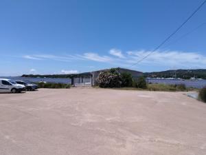 a parking lot with cars parked next to a body of water at Le Golfe in Figari +1 photo