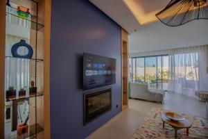 een woonkamer met een open haard en een tv aan de muur bij Villa Marleanis 5 suites esprit Beldi chic chaleureux et contemporain avec piscine chauffée in Marrakesh