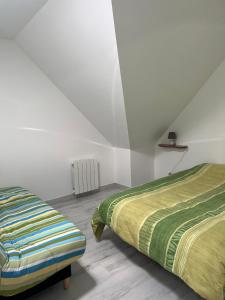 two beds in a room with white walls at Reinettes - 2 in Mulsanne