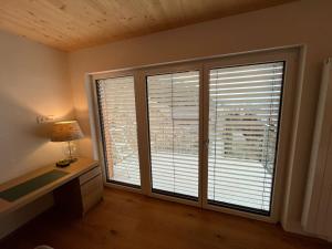 een kamer met 2 grote ramen met jaloezieën bij Apartment Laura in Jenig