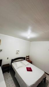 una camera da letto con un letto con un tovagliolo rosso sopra di Hotel Pousada 5 de Abril a Novo Hamburgo Altre 21 foto