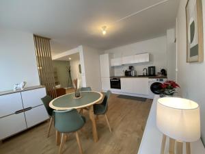 a kitchen and living room with a table and chairs at L'Escapade Cosy Proche Métro CHU et EHESP in Rennes