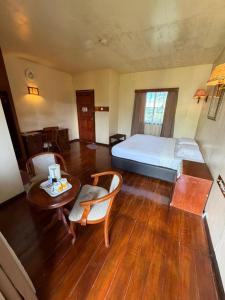 a bedroom with a bed and a table and chairs at Rose Cabin Kundasang in Ranau