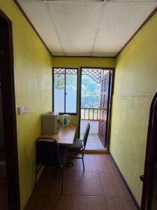 a room with a table and chairs and a window at Rose Cabin Kundasang in Ranau