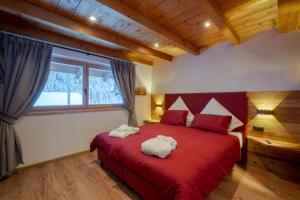 a bedroom with a red bed with two towels on it at Orchidea Suite & SPA Apartments in Canazei