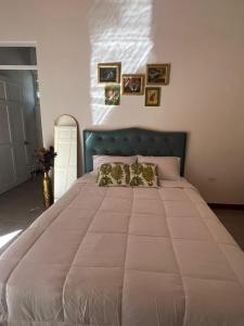 een groot wit bed in een slaapkamer met foto's aan de muur bij Villa Republik in Parrita