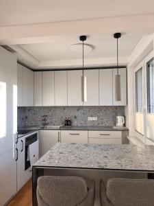 a kitchen with white cabinets and a granite counter top at Apartamentai Akvilė in Šilutė