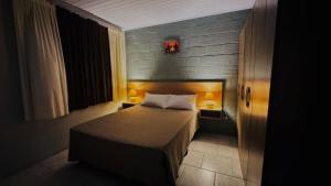 ein kleines Schlafzimmer mit einem Bett und zwei Lampen in der Unterkunft Residencial Solar Três in Imbé