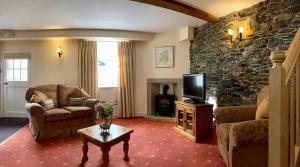ein Wohnzimmer mit einem TV und einer Steinmauer in der Unterkunft Scale Hill Hotel in Loweswater