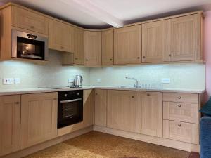 eine Küche mit Holzschränken und einer Mikrowelle in der Unterkunft Scale Hill Hotel in Loweswater