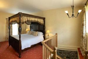 ein Schlafzimmer mit einem Himmelbett und einer Treppe in der Unterkunft Scale Hill Hotel in Loweswater
