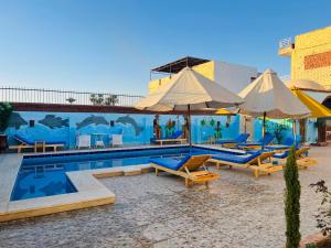 a pool with chairs and umbrellas next to a mural at Horus Golden Luxor in Luxor