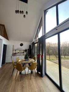 a dining room with a table and chairs and large windows at Arbor in Vadul lui Carol II