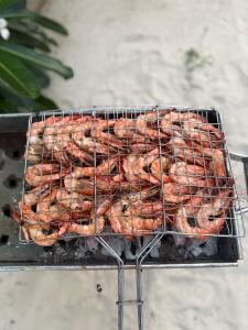 a bunch of sausages cooking on a grill at Zanzi coconut house in Jambiani