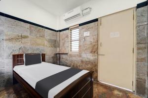 een slaapkamer met een bed in een kamer met stenen muren bij Prm classic lodge in Erode