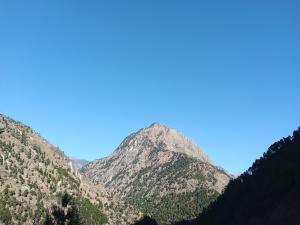 een berg met een blauwe lucht op de achtergrond bij the clifton chapter tirthan in Banjār +1 foto