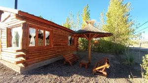 une cabine avec un parasol et deux chaises et un anapa dans l'établissement Cabañas Angualasto, à Uspallata