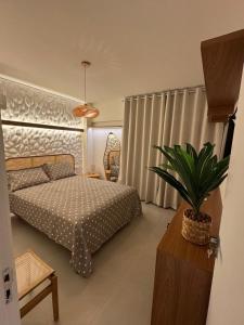 a bedroom with a bed and a potted plant at Praia do Rosa Park Studio in Guarapari
