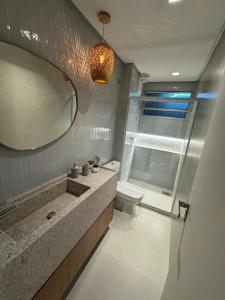 a bathroom with a sink and a toilet and a mirror at Praia do Rosa Park Studio in Guarapari