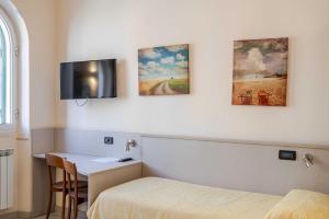 a room with two beds and a desk and a tv at Hotel POSTA - Comfortable Stay in Ventimiglia in Ventimiglia