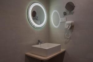 a bathroom with a sink and two mirrors on the wall at Hotel De Blossom in Guwahati +22 photos