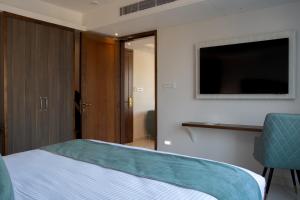 a bedroom with a bed and a flat screen tv at Hotel De Blossom in Guwahati