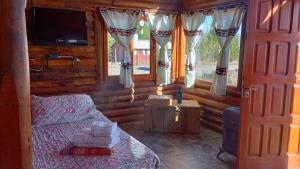 une chambre avec un lit, une télévision et des fenêtres dans l'établissement Cabañas Angualasto, à Uspallata