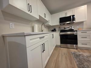 La cuisine est équipée de placards blancs et d'un four micro-ondes noir. dans l'établissement Quiet Comfort Suite, à Moncton 10 autres photos