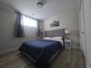 une chambre avec un lit avec une couette bleue et une fenêtre dans l'établissement Quiet Comfort Suite, à Moncton