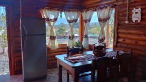 une cuisine avec une table et un réfrigérateur et une fenêtre dans l'établissement Cabañas Angualasto, à Uspallata