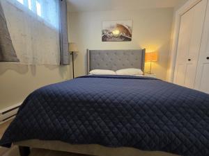 - un lit avec une couette bleue dans une chambre dans l'établissement Quiet Comfort Suite, à Moncton