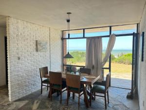 a dining room with a table and chairs and a large window at Itamar Lodge in La Coronilla