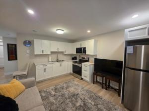  La cuisine est équipée de placards blancs, d'un canapé et d'un réfrigérateur. dans l'établissement Quiet Comfort Suite, à Moncton