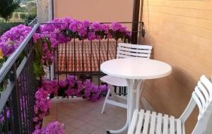 two chairs and a table on a balcony with purple flowers at B&B Amurri Domenica in Grottammare