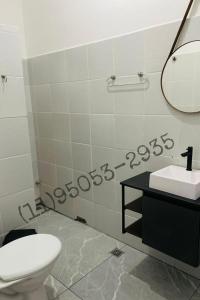 een badkamer met een toilet, een wastafel en een spiegel bij Bertioga Rio da Praia in Bertioga