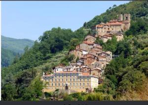 a village on a hill with a building on it at La Fatina appartamento in Collodi