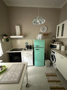 a kitchen with a green refrigerator and white cabinets at La Fatina appartamento in Collodi