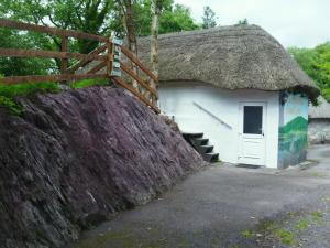a building with a thatched roof and a fence at Thatched 2persons Cottage in Currahy Bridge