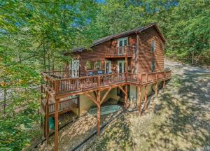een blokhut met een terras in het bos bij Almost Heaven - Grill, 2 King Beds, Wifi, Deck, Pool Access, Hiking, Wood Stove, Family Friendly in Berkeley Springs