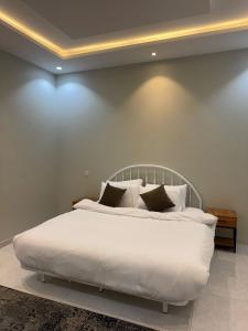 een slaapkamer met een bed met witte lakens en kussens bij Holiday Home Al Taif Al Wisam in Taif