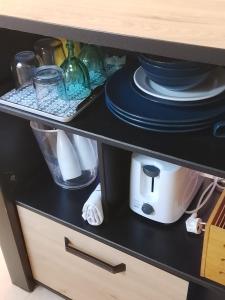 ein schwarzes Regal mit Geschirr und anderen Gegenständen darauf in der Unterkunft SWEET PARADISE STUDIO à 10 mn du centre en voiture in Fort-de-France