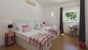 una camera da letto bianca con due letti e una finestra di Casa dos Pelargónios a Luz Altre 61 foto