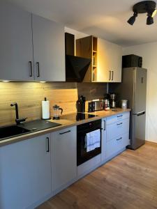 een keuken met witte kasten en roestvrijstalen apparaten bij Ferienwohnung CityNest - moderne Wohnung zentral in Schmallenberg in Schmallenberg +10 foto's