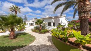 una casa bianca con palme e un vialetto di Casa dos Pelargónios a Luz