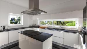 una cucina con mobili bianchi, un lavandino e una finestra di Casa dos Pelargónios a Luz