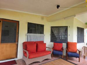 twee stoelen met rode kussens op een veranda bij Tunu House in Viseisei