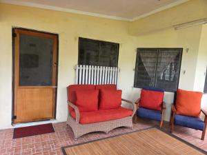 twee stoelen met rode kussens op een veranda bij Tunu House in Viseisei