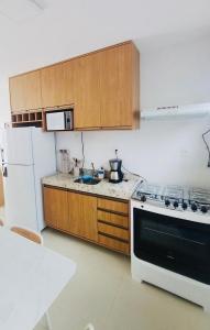 a kitchen with a stove and a white refrigerator at Casa 3 suítes Salinas in Salinópolis