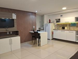 a kitchen with white cabinets and a table and a refrigerator at Nomar VI - Gold Flat in João Pessoa
